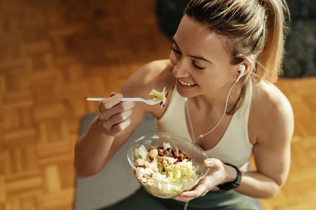 Osoba je sałatkę z miski, przedstawiając zdrowe odżywianie i zbilansowaną dietę.